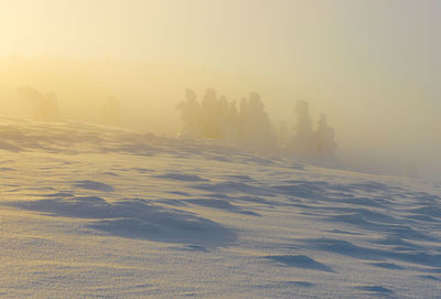 Scenic view of snow covered landscape against sky during sunset