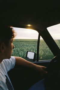 Man sitting in old car watching sunset 