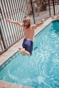Back view of a happy child boy jumping into the pool. happy childhood and summer vacation concert.