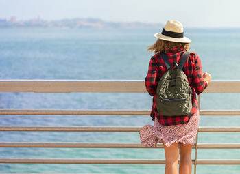 Woman standing by railing against sea