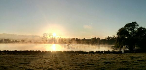 Scenic view of calm lake against sky during sunrise