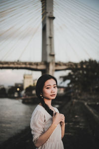 Portrait of woman standing against bridge