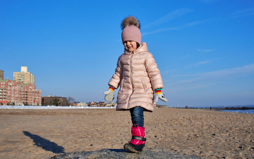 Young girl playing on the beach in winter dressed in a warm coat