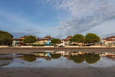 Houses by lake and buildings against sky