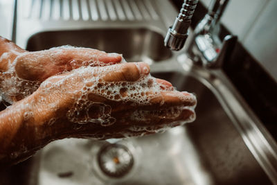 Cropped image of man washing hands in sink