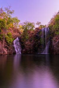 Scenic view of waterfall in forest against sky