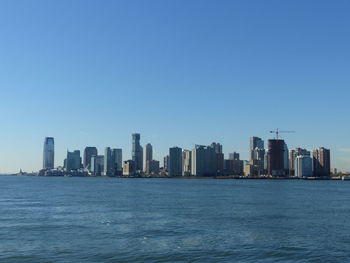 Sea in city against clear blue sky