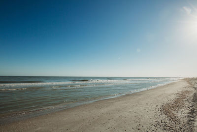 Scenic view of beach against clear blue sky