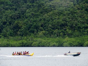 People in boat on river against trees