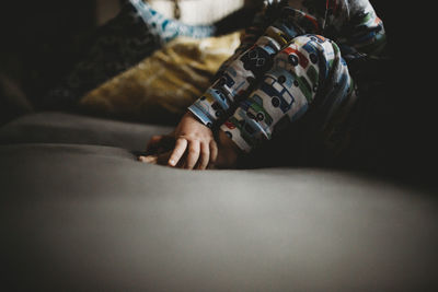 Low section of baby boy sitting on sofa at home