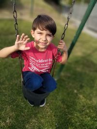 Happy boy playing on swing at playground