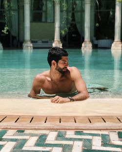 Young man sitting in swimming pool