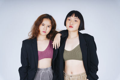 Portrait of lesbian couple wearing blazer against gray background