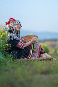 Midsection of woman sitting on land against sky