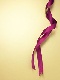 Close-up of red ribbon over yellow background