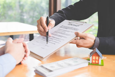 Midsection of man holding paper at table