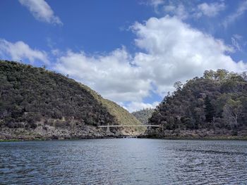 Scenic view of river by mountains against sky