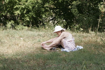 Side view of senior woman sitting on grassy field