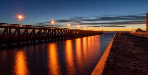 Bridge over river against sky during sunset