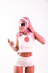 Young woman using phone while standing against white background