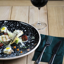 High angle view of carpaccio with salad served in plate by wineglass on table