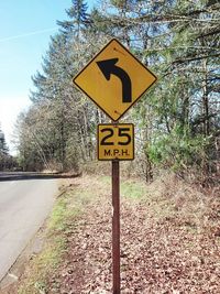 Information sign on road by trees against sky