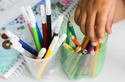 Midsection of person holding colored pencils