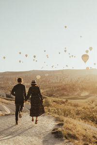 Rear view of people walking on landscape against clear sky