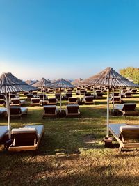 Empty chairs on field against clear blue sky