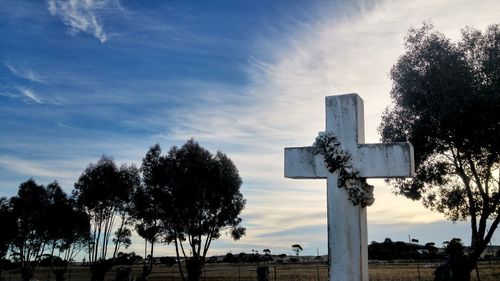 Low angle view of cross at cemetery against sky