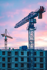 Worksite with cranes, new buildings or houses under construction with workers with helmet at work