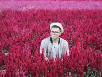 Man standing by red flowering plants on field