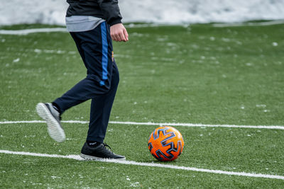 Low section of man playing soccer ball on grass