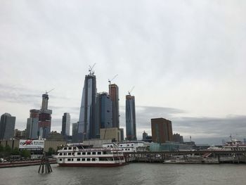 Modern buildings by river against sky in city