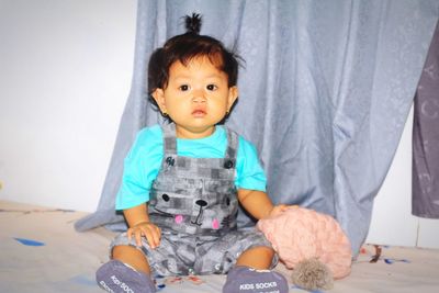 Portrait of cute baby girl sitting with toy