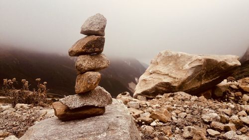 Stack of stones on rock against sky