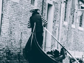 Rear view of man standing on boat against building