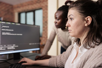 Side view of young woman using laptop at home