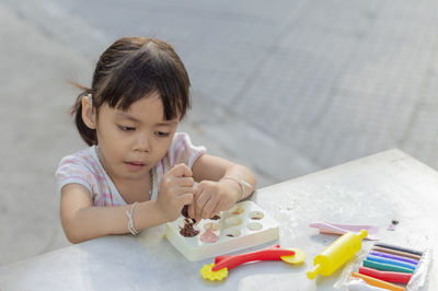 Close-up of cute girl playing with childs play clay at table outdoors