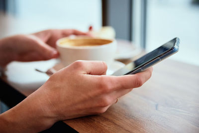 Woman have breakfast at cafe, use smartphone at cafe