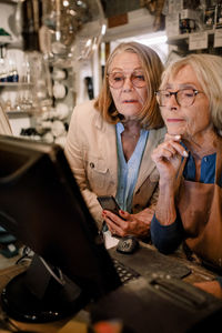 Senior female customer and saleswoman looking at computer monitor in hardware store