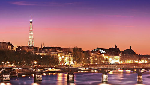 Bridge over river in city at dusk