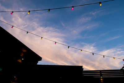 Low angle view of silhouette lanterns hanging against sky at dusk