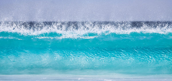 Close-up of sea wave splashing against blue sky