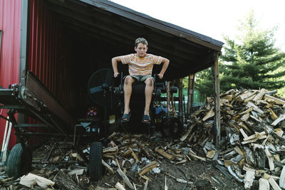 Full length of boy sitting on equipment in warehouse