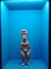 Full length of father with toy sitting against blue wall