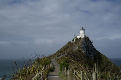 Lighthouse by sea against sky