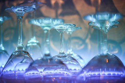 Close-up of wineglasses arranged on illuminated shelf in bar