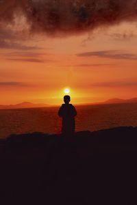 Silhouette of people on beach at sunset