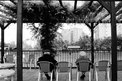 Rear view of people sitting on seat in city